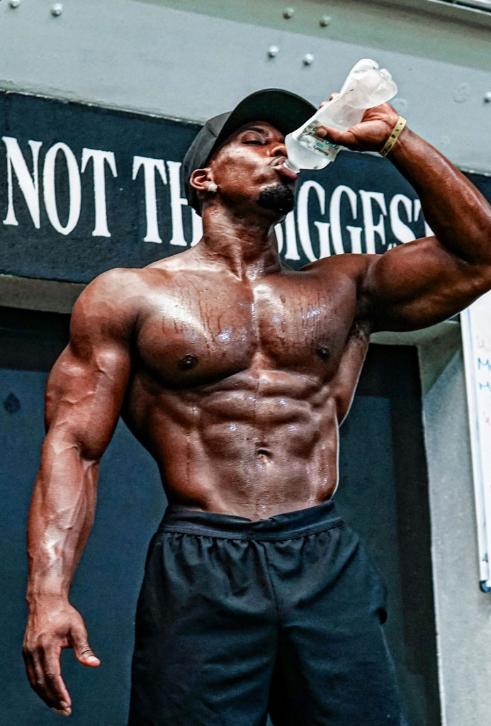 Coach is drinking water and showing his abs muscles.